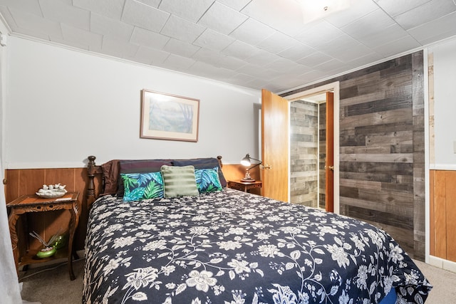 bedroom with carpet, wooden walls, and a wainscoted wall