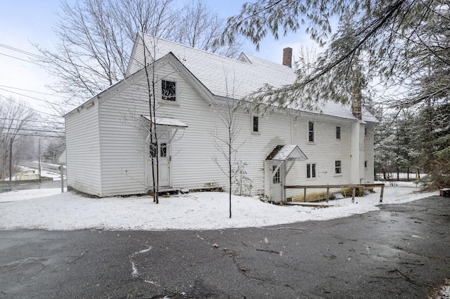 snow covered property featuring a chimney