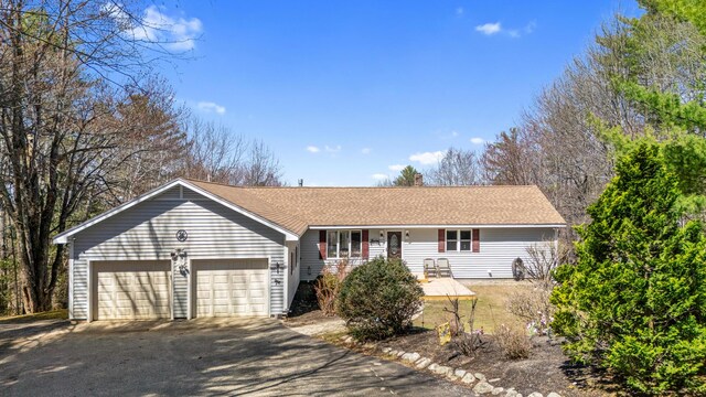 ranch-style home with a shingled roof, an attached garage, and aphalt driveway