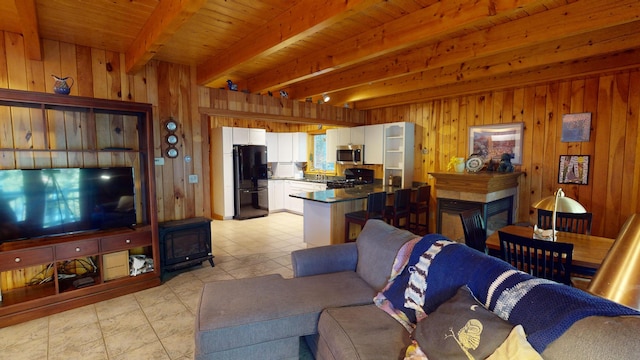 86 Webb Cove Dr, Lowell, ME 04493 - living room with beamed ceiling, light tile patterned floors, a multi sided fireplace, and wood walls