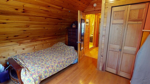 86 Webb Cove Dr, Lowell, ME 04493 - bedroom with wooden walls, light wood finished floors, vaulted ceiling, and a closet