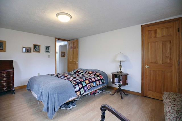 bedroom featuring a textured ceiling, wood finished floors, and baseboards