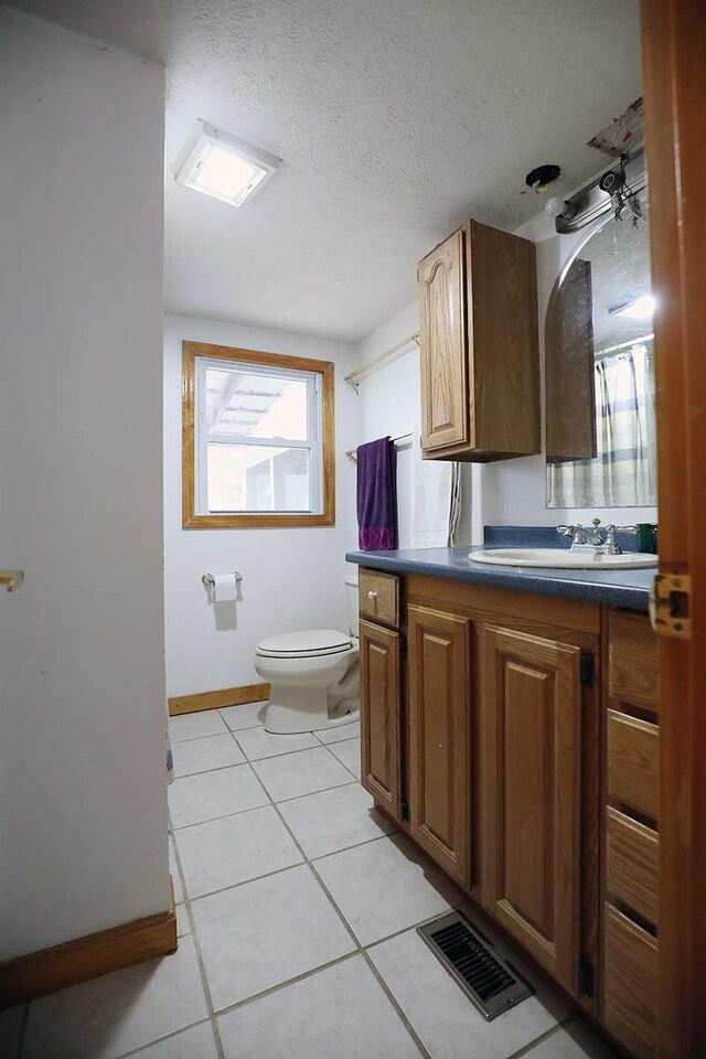 bathroom with vanity, toilet, visible vents, baseboards, and a textured ceiling