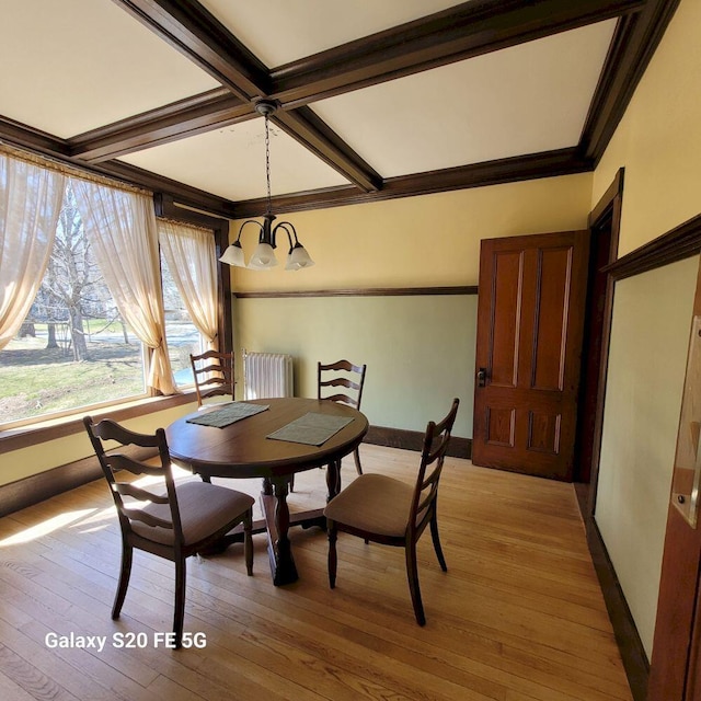 dining room with beamed ceiling, coffered ceiling, light wood-type flooring, radiator heating unit, and a notable chandelier