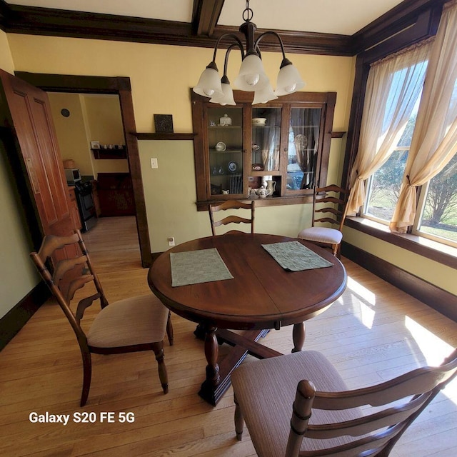 dining room with ornamental molding, light wood finished floors, and baseboards