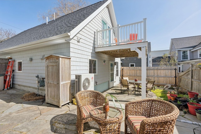 rear view of property with a balcony, a patio, a fenced backyard, roof with shingles, and outdoor dining space
