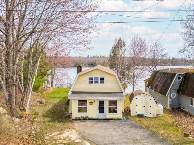 dutch colonial featuring a chimney, an outbuilding, a storage unit, and a gambrel roof