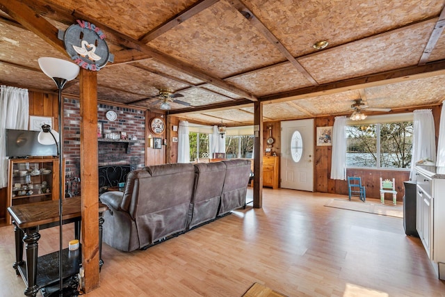 living room with wood walls, a brick fireplace, ceiling fan, and wood finished floors