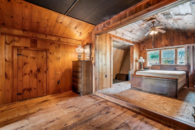 bathroom with a ceiling fan, wood walls, vaulted ceiling, and hardwood / wood-style floors