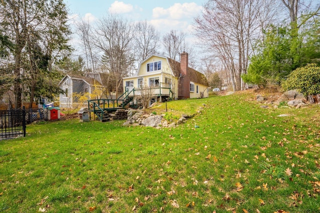 view of yard with fence, a wooden deck, and stairway