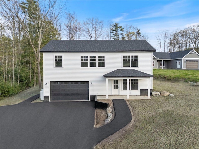 traditional home with an attached garage, driveway, a front lawn, and roof with shingles