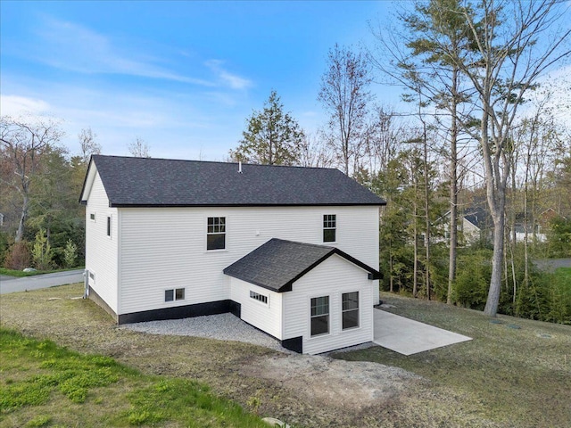 view of side of property with a patio area and a shingled roof
