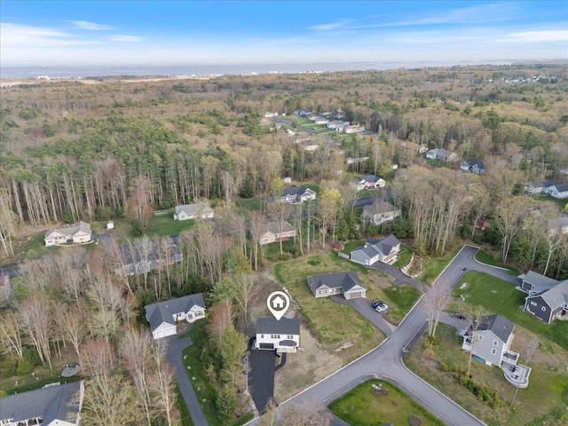 aerial view of property and surrounding area featuring a forest and nearby suburban area