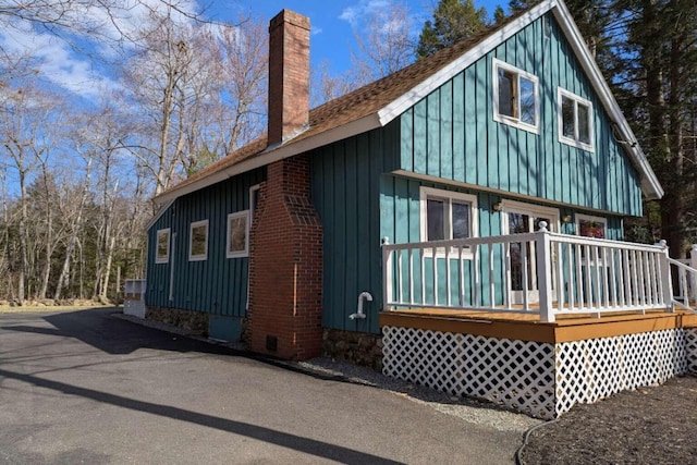 rear view of house featuring board and batten siding and a chimney
