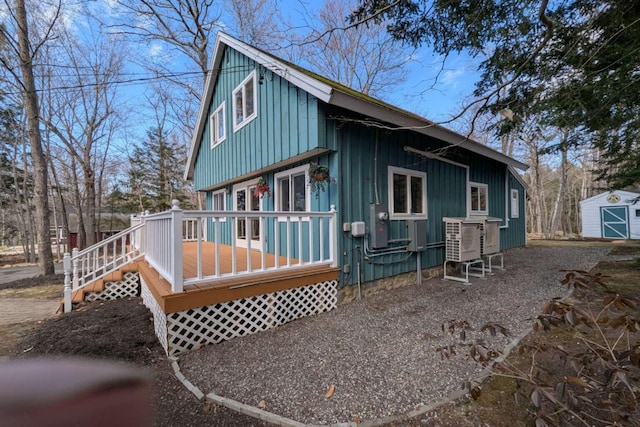 view of property exterior featuring an outdoor structure, a storage unit, board and batten siding, and a deck
