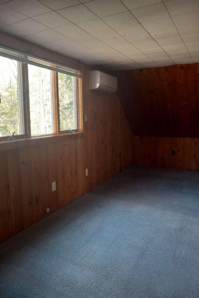 bonus room featuring wood walls, carpet floors, and a wall unit AC