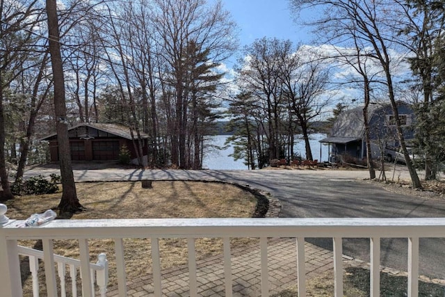 view of yard featuring a balcony, a water view, and aphalt driveway