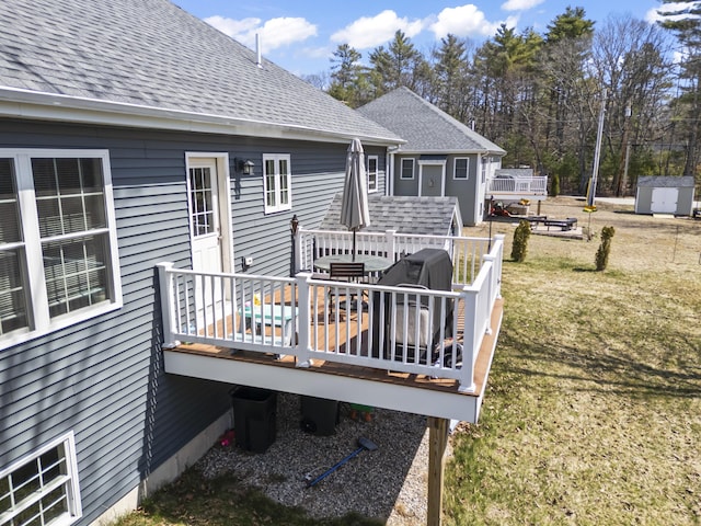 wooden terrace with a storage unit, an outdoor structure, and a yard