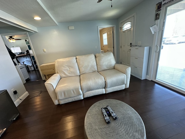 living room with dark wood-style flooring, ceiling fan, and baseboards
