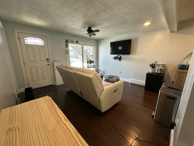 living area with baseboard heating, dark wood-style flooring, a ceiling fan, and a textured ceiling
