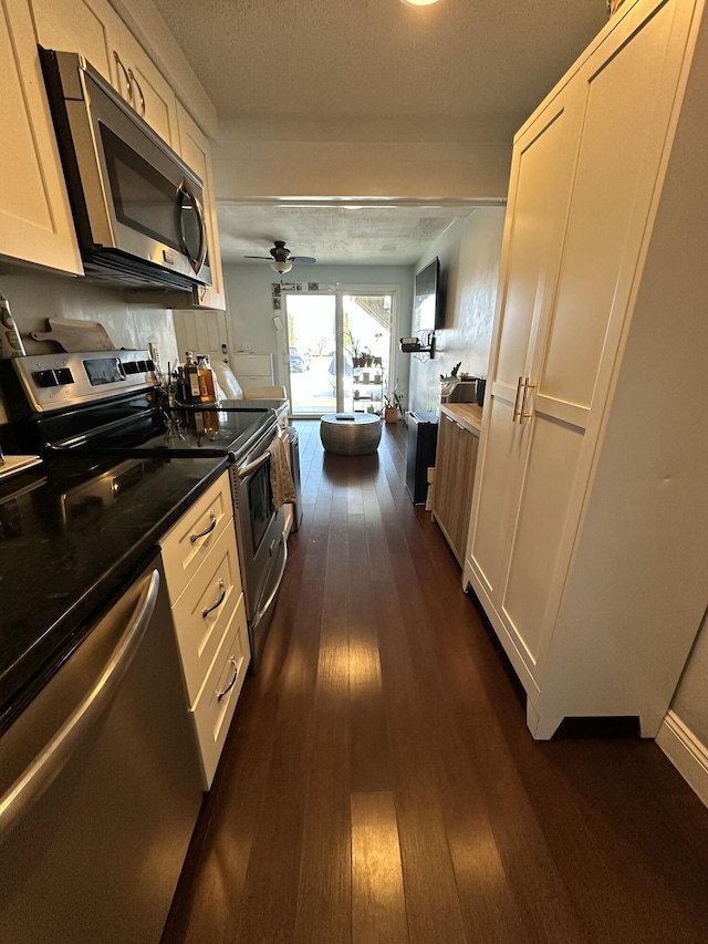 kitchen with a ceiling fan, a textured ceiling, white cabinets, appliances with stainless steel finishes, and dark wood-style floors