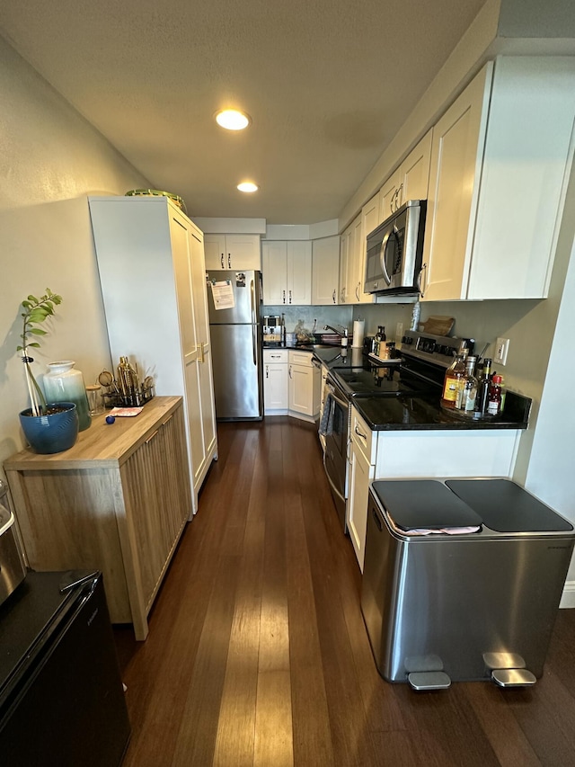 kitchen featuring recessed lighting, appliances with stainless steel finishes, white cabinets, a sink, and dark wood-style floors