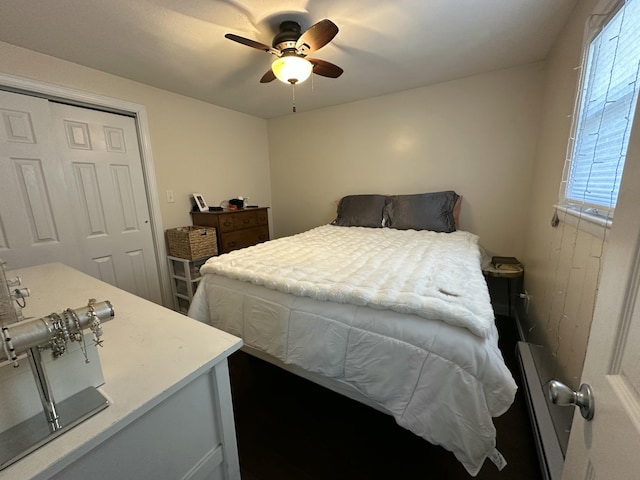 bedroom featuring a baseboard heating unit, a closet, and ceiling fan