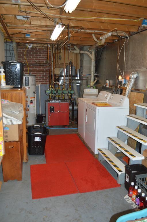 unfinished basement with water heater, washing machine and clothes dryer, and a heating unit