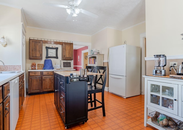 kitchen with a sink, light floors, a kitchen breakfast bar, and white appliances