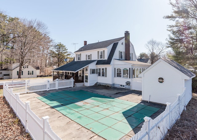 rear view of house with a fenced in pool, a chimney, a sunroom, and a fenced backyard