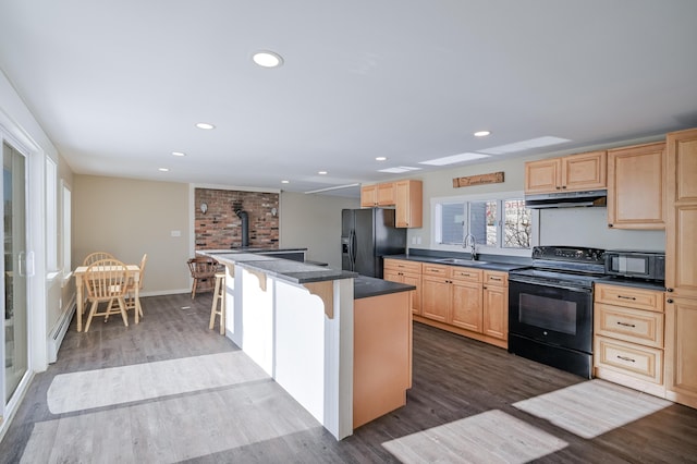 93 Pond Rd, Albion, ME 04910 - kitchen featuring light brown cabinets, under cabinet range hood, black appliances, a sink, and a wood stove