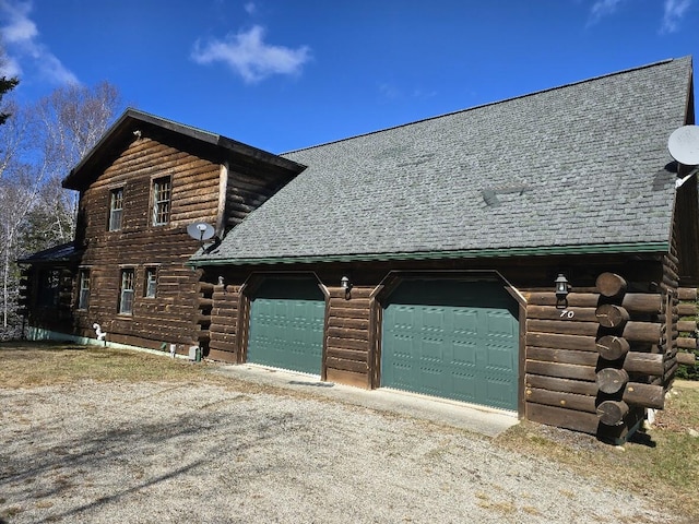 view of side of property featuring roof with shingles, dirt driveway, and log siding