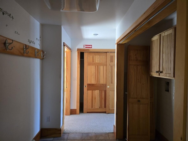 hall with carpet floors and tile patterned flooring