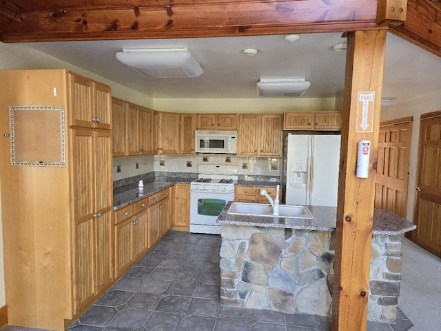 kitchen featuring dark stone counters, white appliances, dark tile patterned floors, and a sink