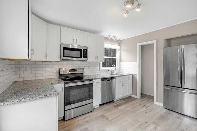 155 Saco Rd, Hollis, ME 04042 - kitchen with appliances with stainless steel finishes, a sink, white cabinetry, light wood-style flooring, and tasteful backsplash