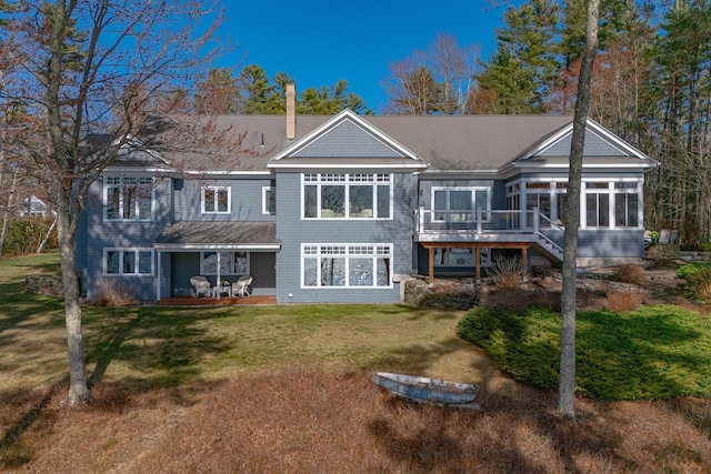 back of house with a yard, a wooden deck, a sunroom, and roof with shingles