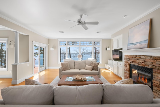 living room with light wood finished floors, a fireplace, crown molding, a ceiling fan, and visible vents