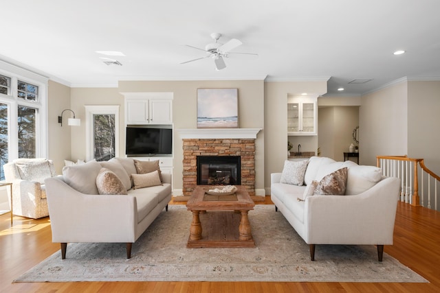 living area with visible vents, wood finished floors, a ceiling fan, and crown molding