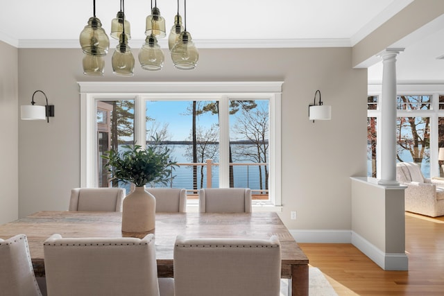 dining space featuring wood finished floors, plenty of natural light, ornamental molding, and decorative columns