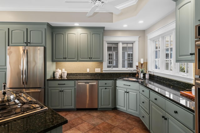 kitchen featuring dark stone counters, tasteful backsplash, a sink, stainless steel appliances, and a ceiling fan