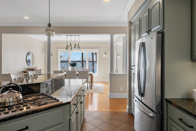 kitchen featuring dark stone counters, decorative columns, tile patterned floors, crown molding, and appliances with stainless steel finishes