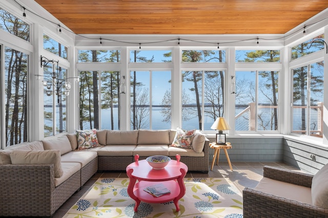 sunroom with tile patterned floors, wooden ceiling, and a water view