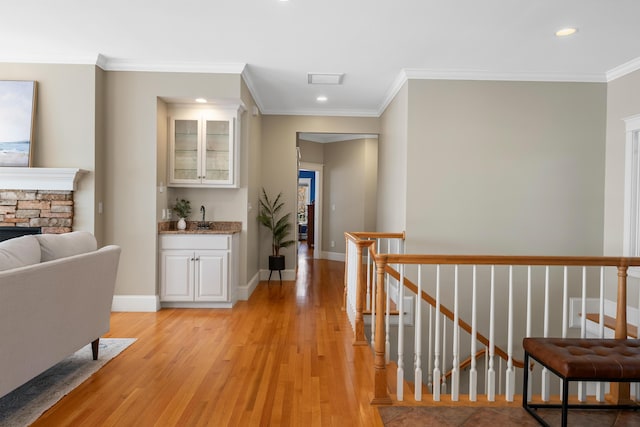 hallway with recessed lighting, light wood-style floors, an upstairs landing, crown molding, and baseboards