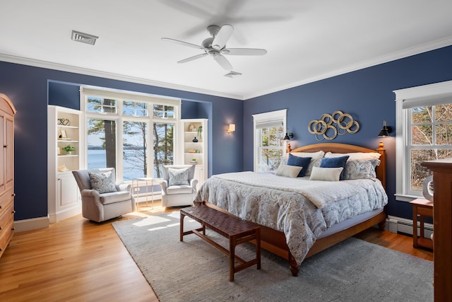 bedroom featuring a baseboard heating unit, visible vents, and multiple windows