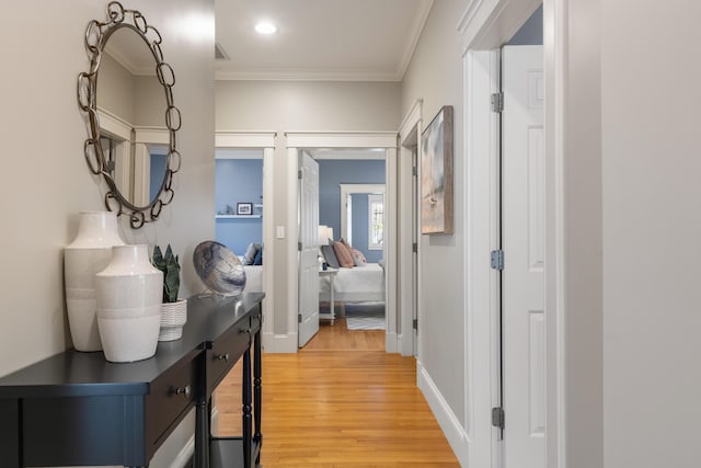 corridor featuring ornamental molding, light wood-style flooring, and baseboards