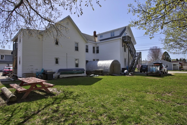 back of house with a lawn, heating fuel, and a chimney