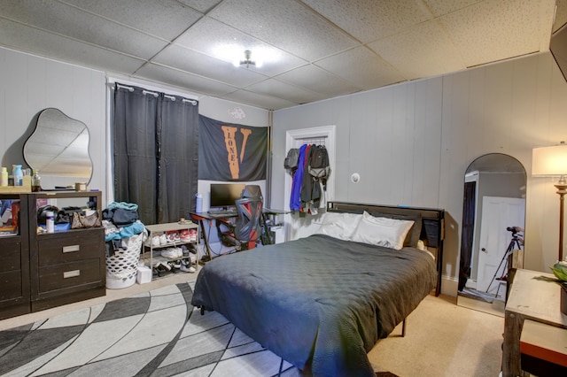 bedroom featuring a decorative wall and a drop ceiling