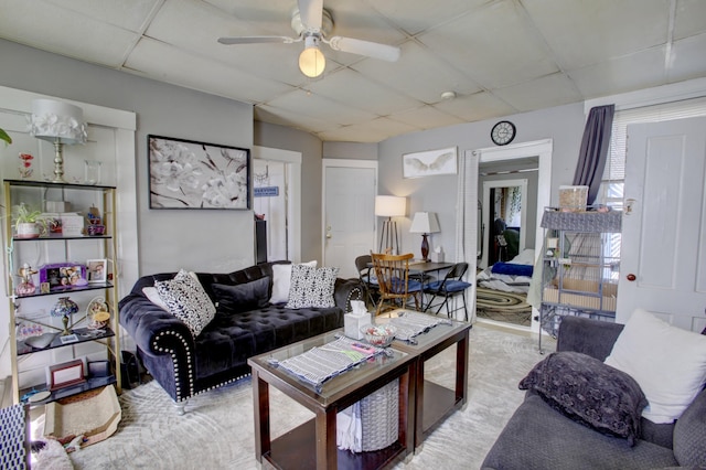 living room with a ceiling fan and a drop ceiling