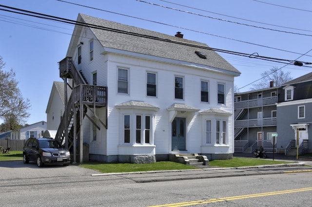 view of front of house with stairway and roof with shingles