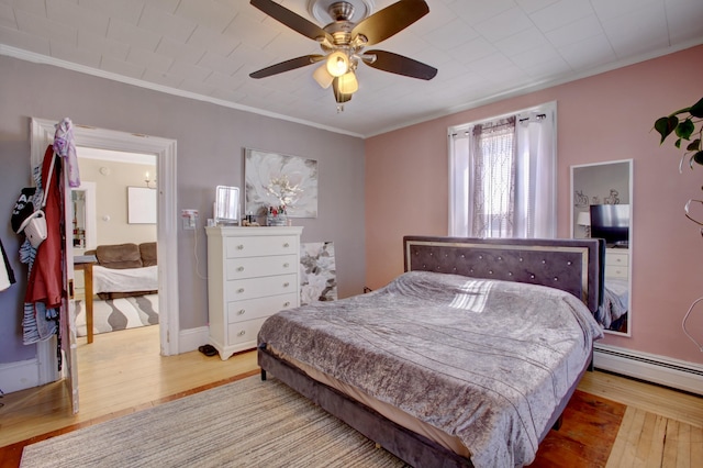 bedroom featuring a baseboard radiator, ornamental molding, a ceiling fan, and wood finished floors